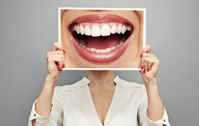 Woman holding image of mouth close up in front of her face